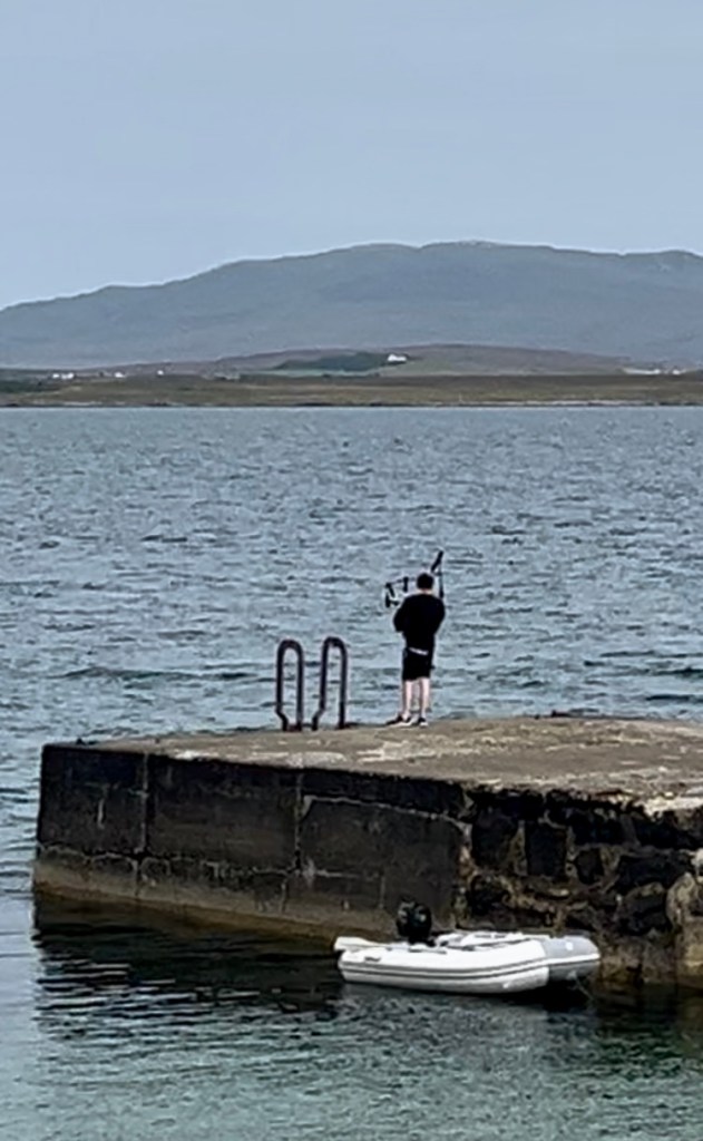 Boy playing bagpipes on a pier