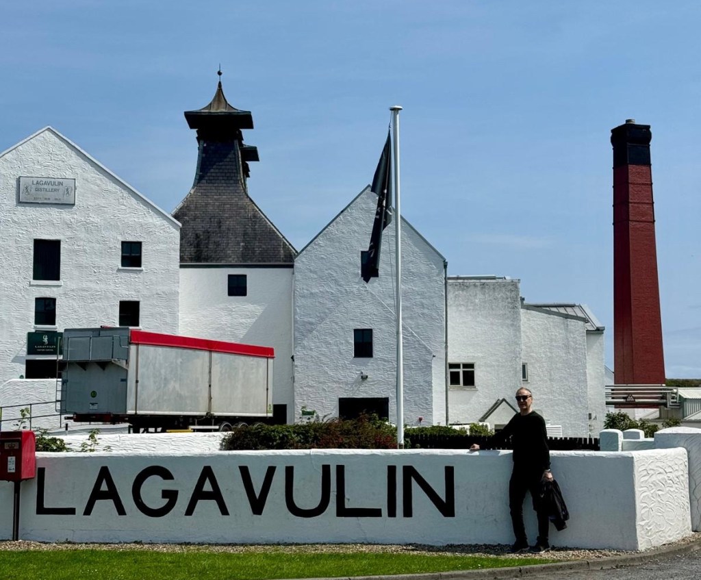 Man standing in front of Lagavulin Distillery, Islay, Scotland